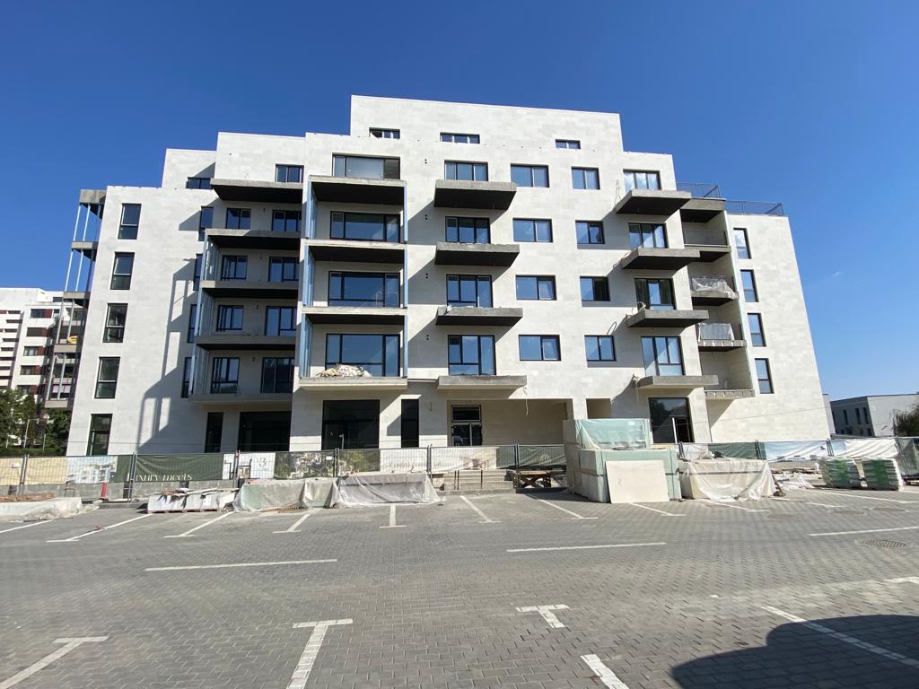 Fațada principală a unui bloc de locuințe din piatră flexibilă deschisă, cu balcoane suprapuse