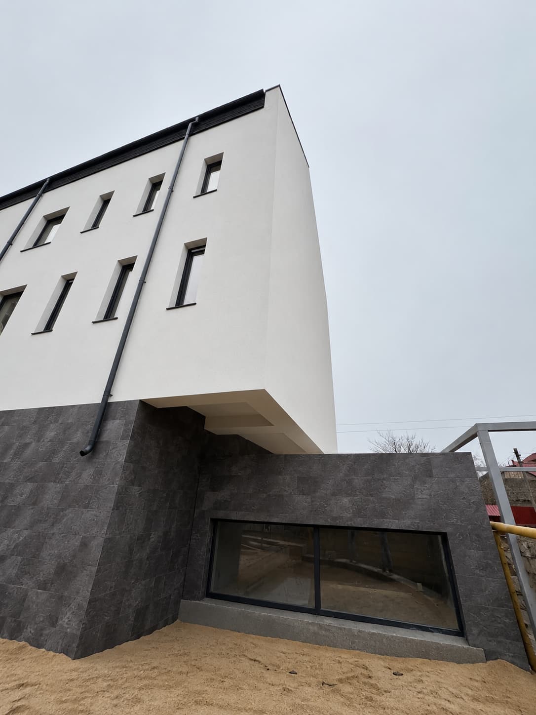 Perete lateral alb cu soclu placat Royal Granite și anexa joasă cu fereastră orizontală