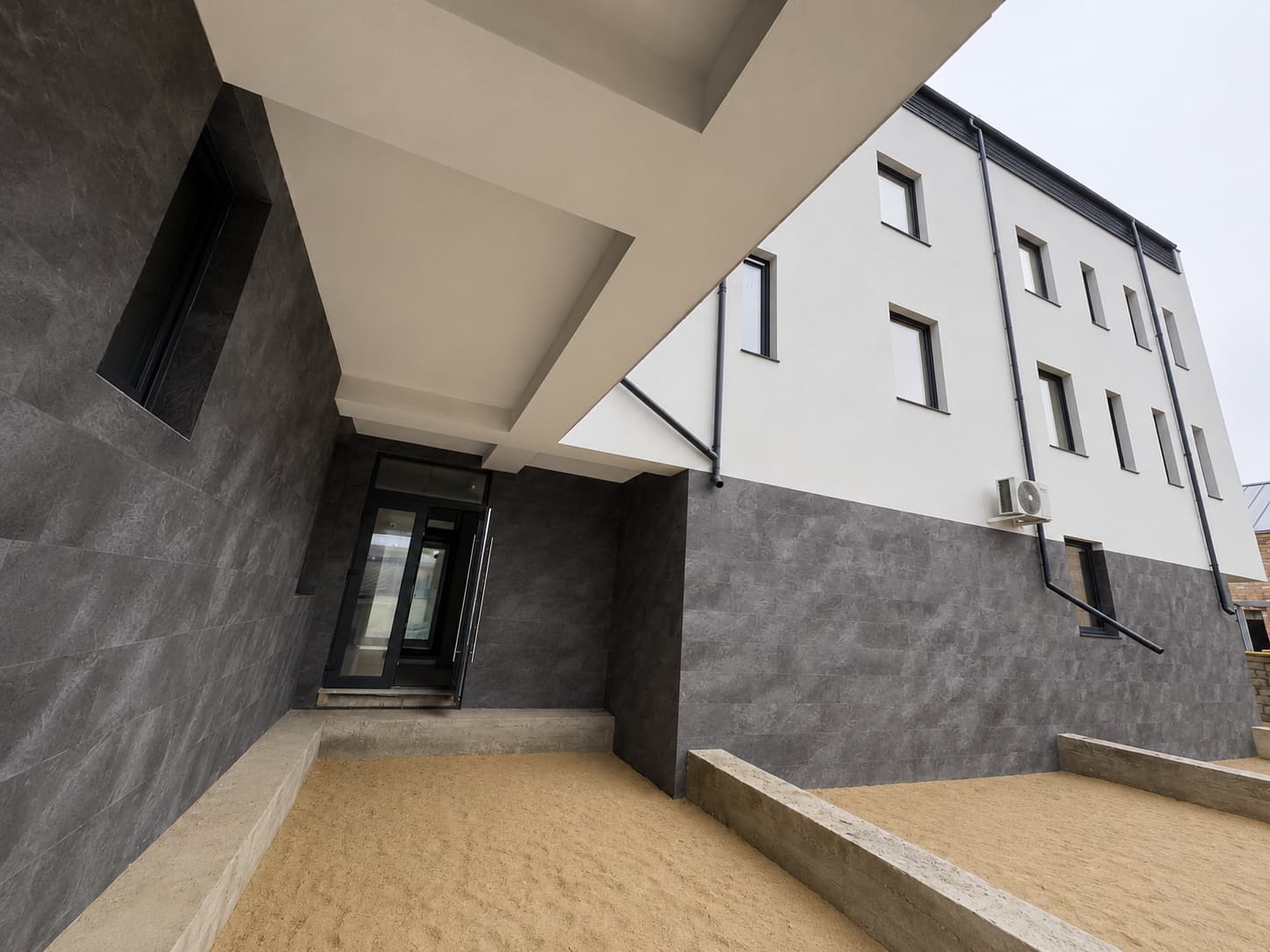 Intrarea secundară sub consolă, cu pereți placați Royal Granite și trepte din beton