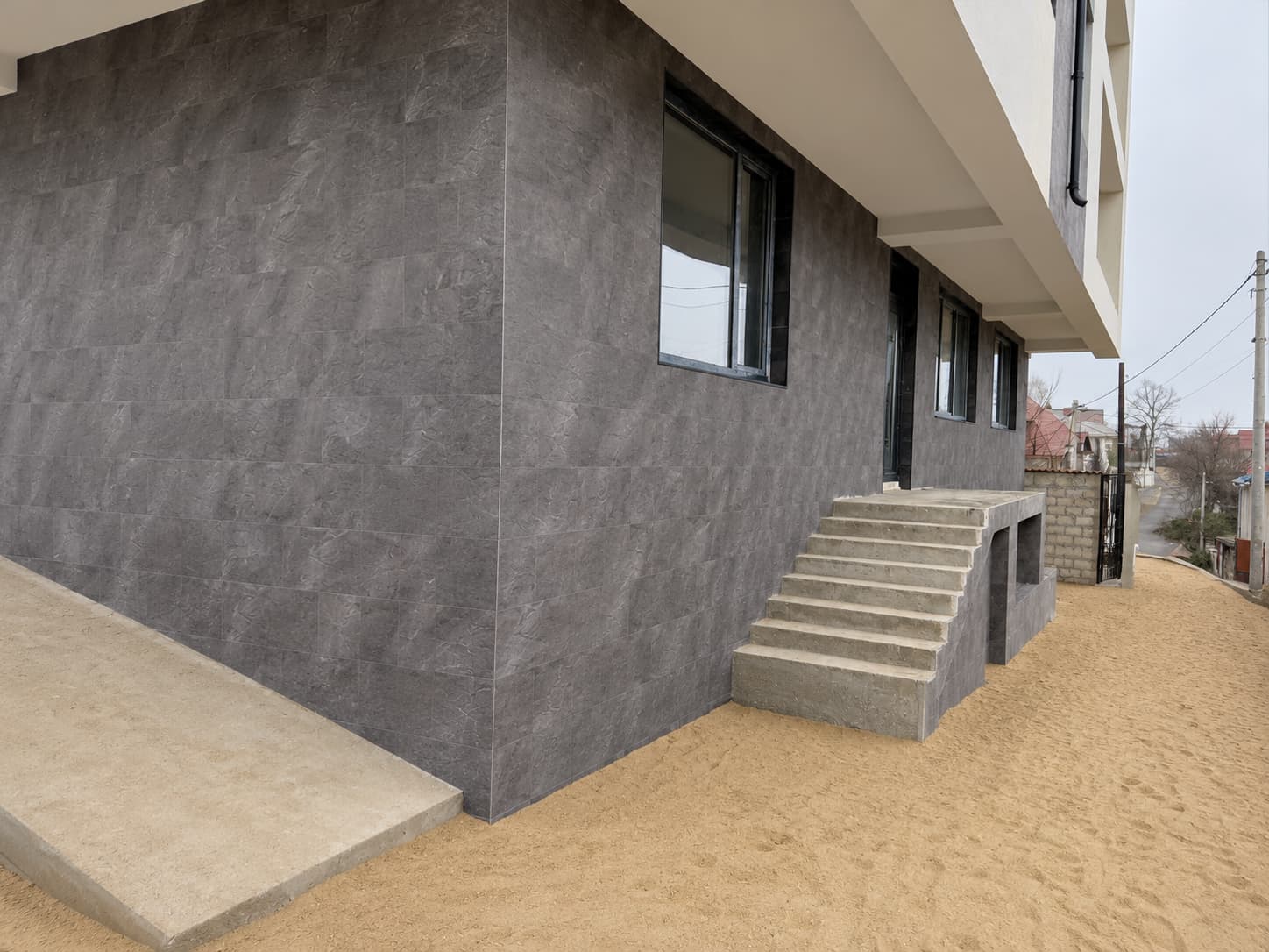 Colț de parter placat Royal Granite, cu rampă din beton și trepte spre intrare
