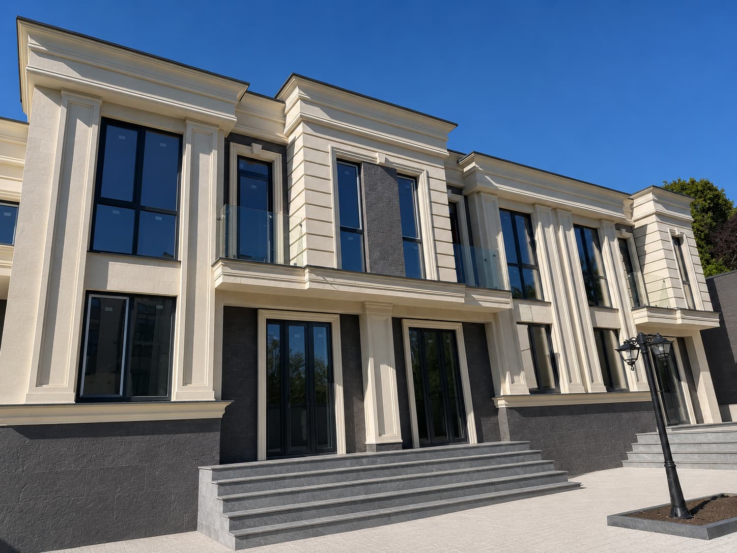 Șir de case cu fațade bej, panouri verticale antracit între ferestre, soclu antracit și trepte