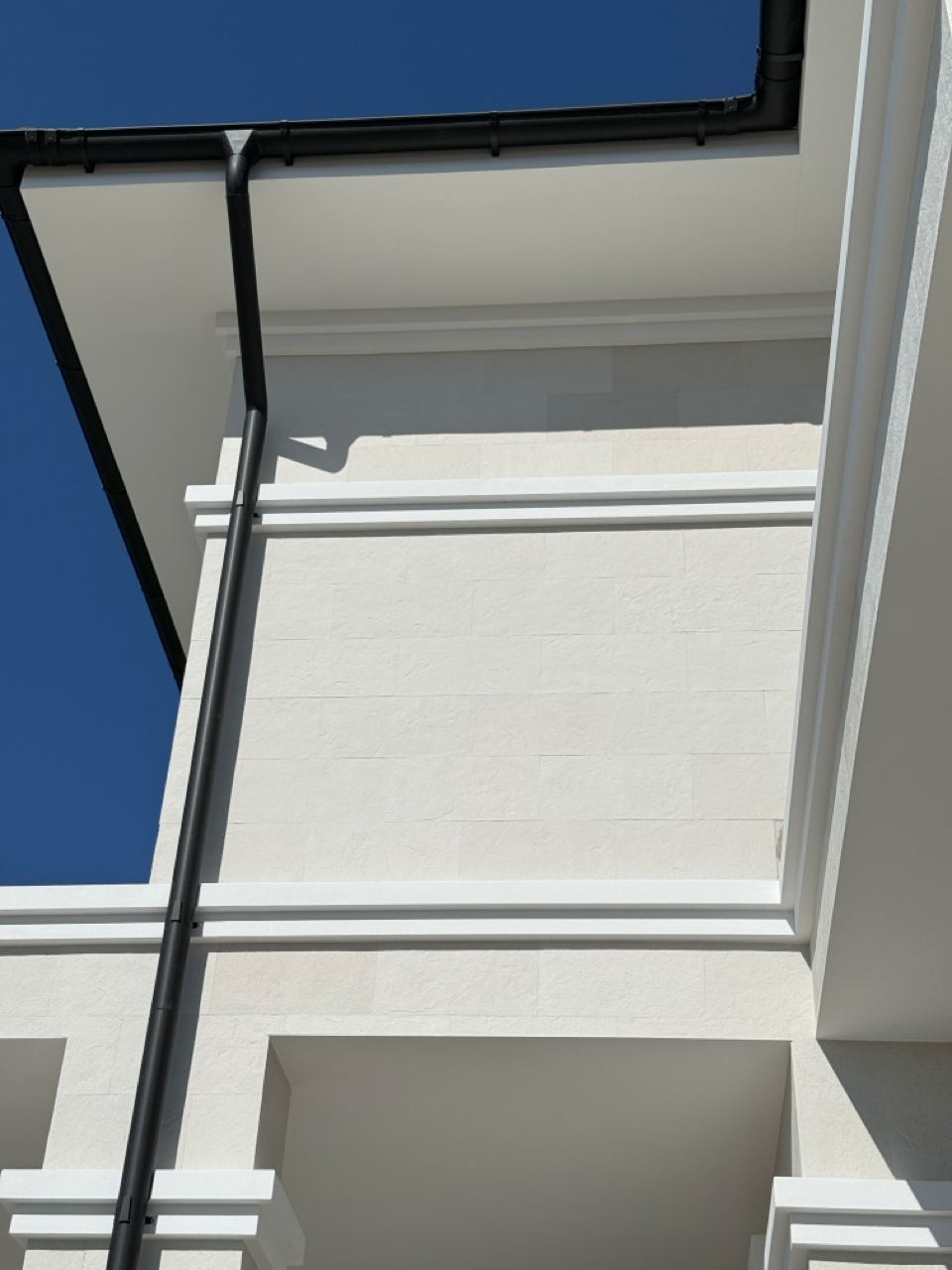 Colț superior cu cornișă albă și partea de jos a balconului, piatră flexibilă deschisă
